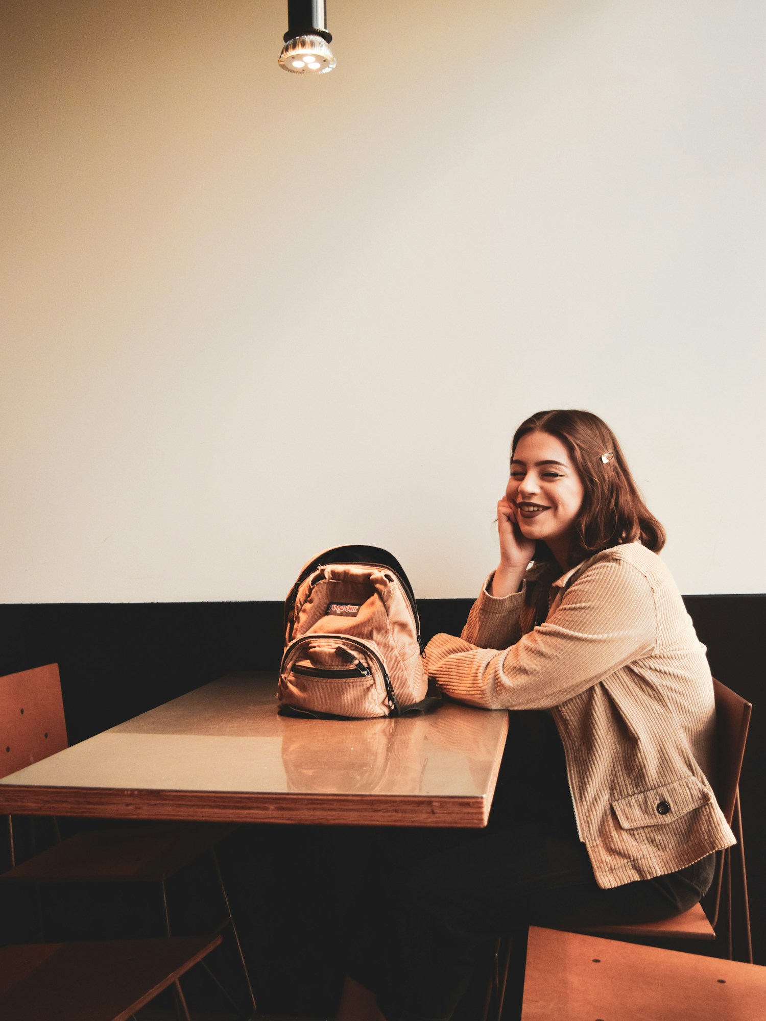 Editorial portrait of a woman seated at a cafe with a Rajbita satchel